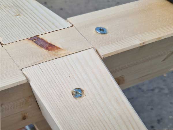 Encuentro entre vigas de madera laminada de pares con la cumbrera del cenador a dos aguas con el refuerzo de tornilleria de acero