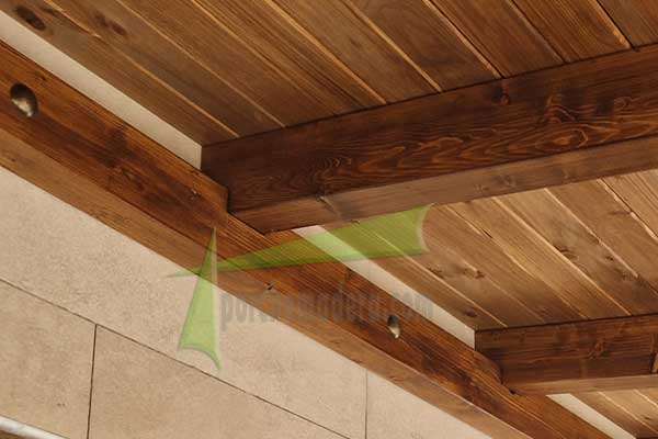 Detalle de cajeado sobre viga de pared en porche de madera color nogal